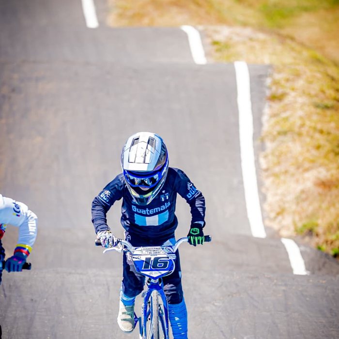 Piloto de BMX Race acelerando en la recta de una pista de competencia